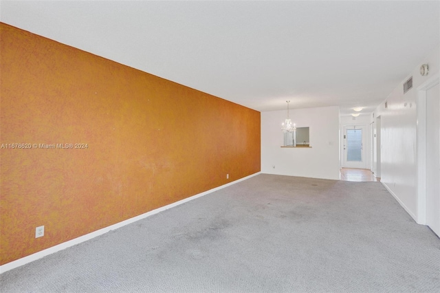 carpeted empty room with a notable chandelier