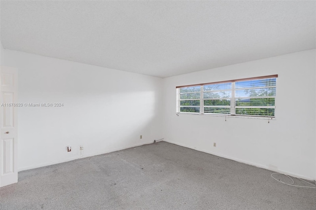 unfurnished room featuring carpet flooring and a textured ceiling