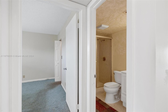 bathroom featuring tiled shower, a textured ceiling, and toilet