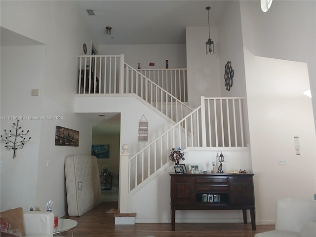 stairway with a towering ceiling and hardwood / wood-style flooring