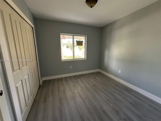 unfurnished bedroom featuring a closet and dark wood-type flooring