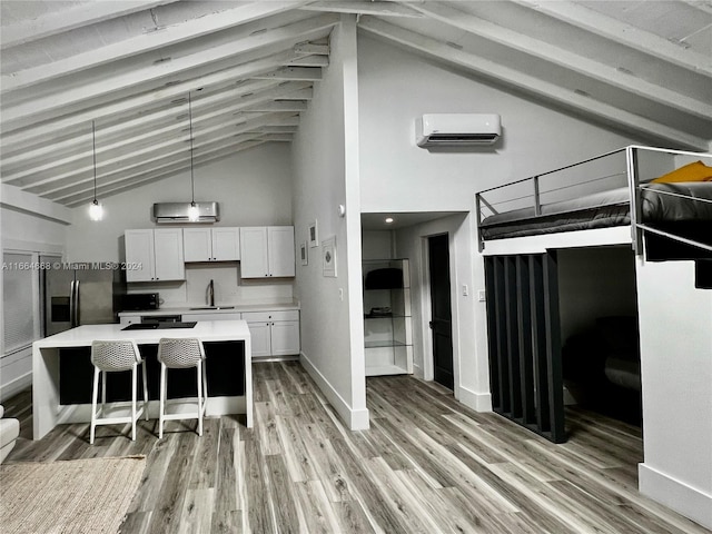 kitchen featuring stainless steel fridge, beamed ceiling, pendant lighting, a wall unit AC, and white cabinets