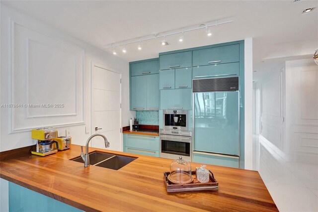 kitchen featuring paneled fridge, butcher block counters, sink, and light tile patterned floors