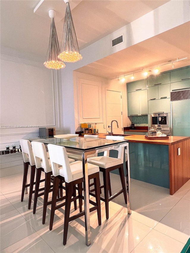 dining space featuring sink, rail lighting, and light tile patterned floors