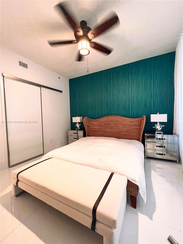 tiled bedroom with a closet, ceiling fan, and a textured ceiling