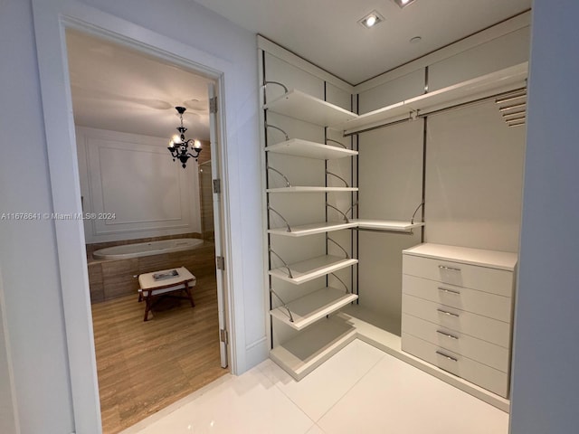 spacious closet featuring a notable chandelier and light wood-type flooring