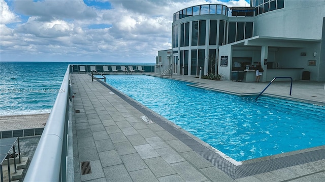 view of pool featuring a water view and a patio