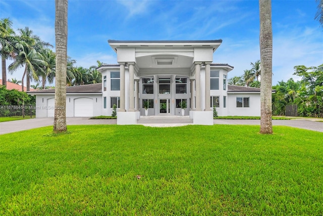 view of front of house with a garage, concrete driveway, a front lawn, and stucco siding