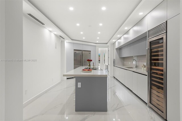 kitchen featuring black electric stovetop, a kitchen island, sink, beverage cooler, and gray cabinets