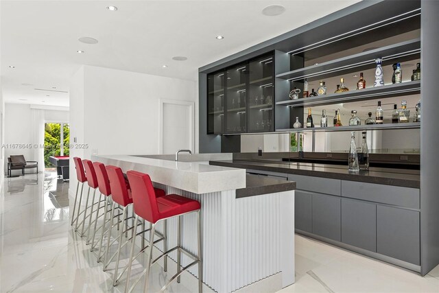 interior space with gray cabinets, dark stone countertops, and sink