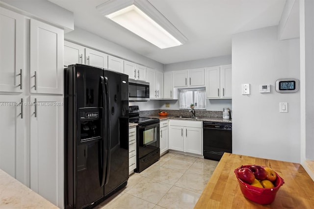 kitchen with white cabinets, black appliances, sink, and butcher block countertops