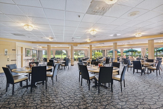 carpeted dining area with a paneled ceiling