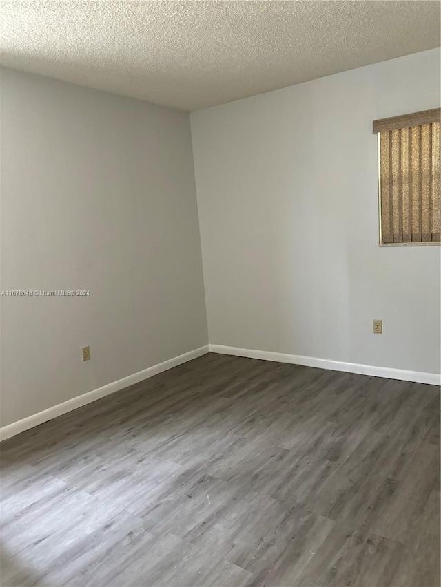 unfurnished room with dark wood-type flooring and a textured ceiling