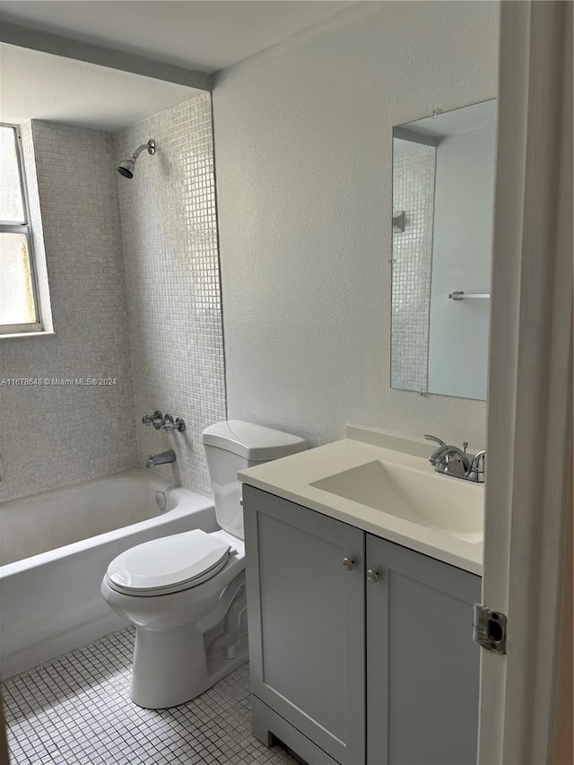 full bathroom featuring tiled shower / bath, vanity, toilet, and tile patterned floors