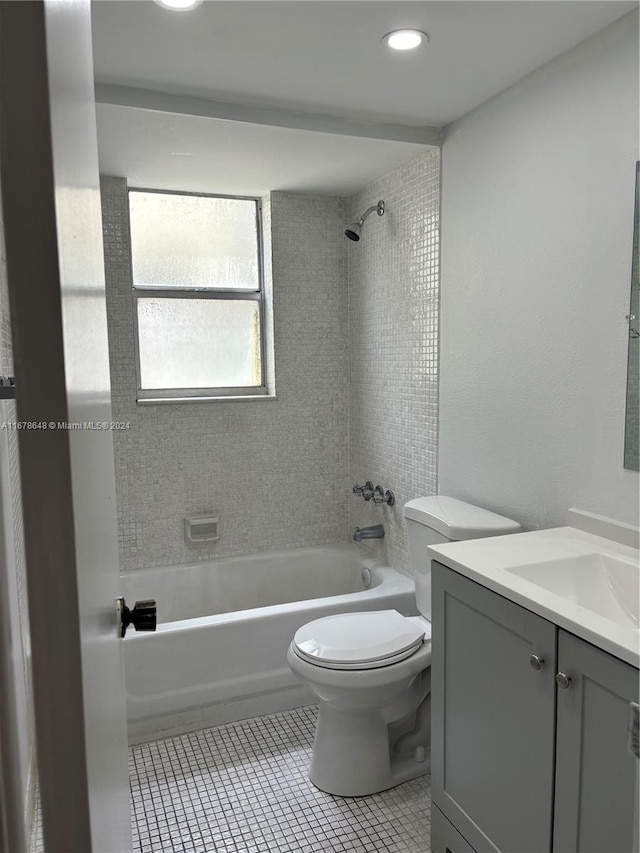 full bathroom with toilet, tiled shower / bath, vanity, and tile patterned flooring