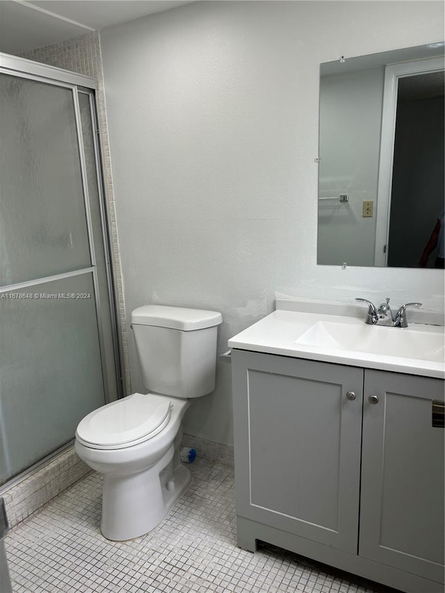 bathroom featuring vanity, toilet, tile patterned floors, and a shower with door