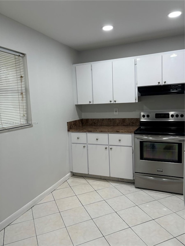 kitchen with stainless steel electric range, light tile patterned floors, and white cabinets