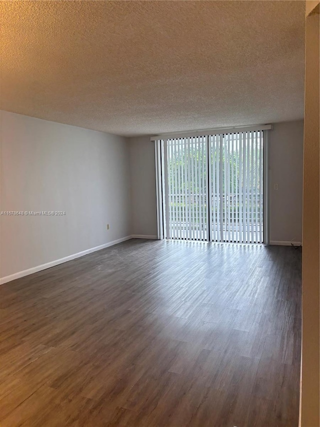 spare room with a textured ceiling and dark wood-type flooring