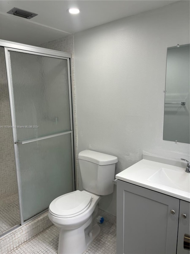 bathroom with vanity, tile patterned flooring, toilet, and walk in shower