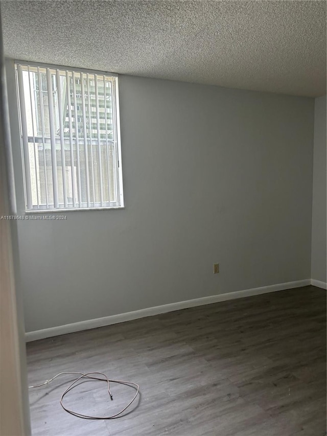 spare room featuring hardwood / wood-style floors and a textured ceiling