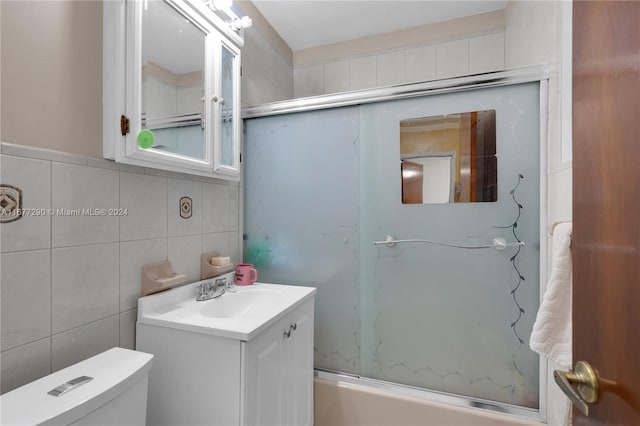 full bathroom with vanity, enclosed tub / shower combo, toilet, and tile walls