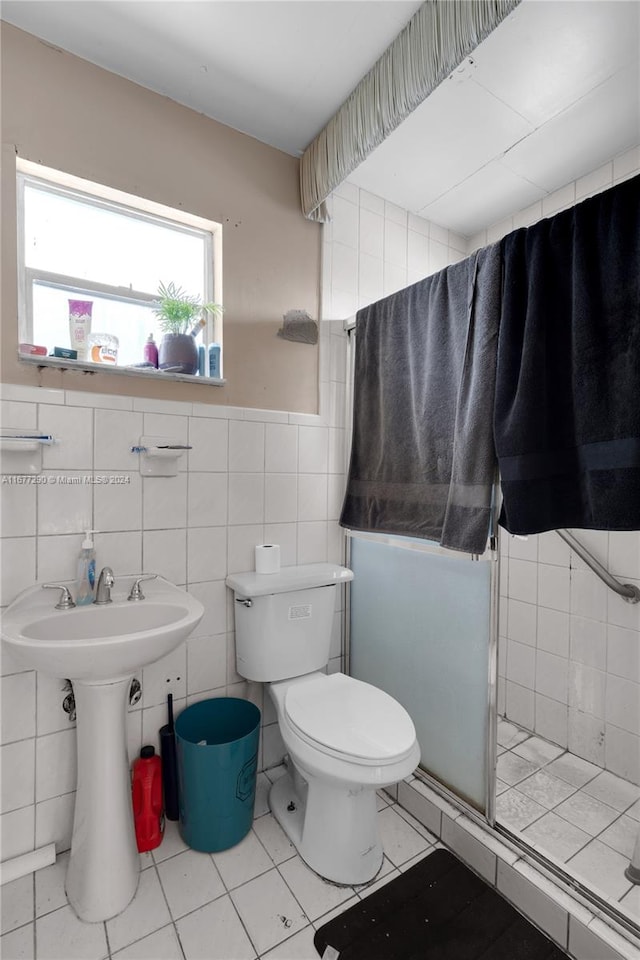 bathroom featuring a shower with door, tile walls, toilet, and tile patterned flooring