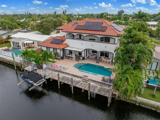 rear view of house featuring a patio, a water view, and solar panels