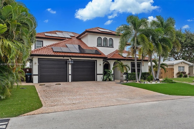 mediterranean / spanish house with a garage, a front lawn, and solar panels