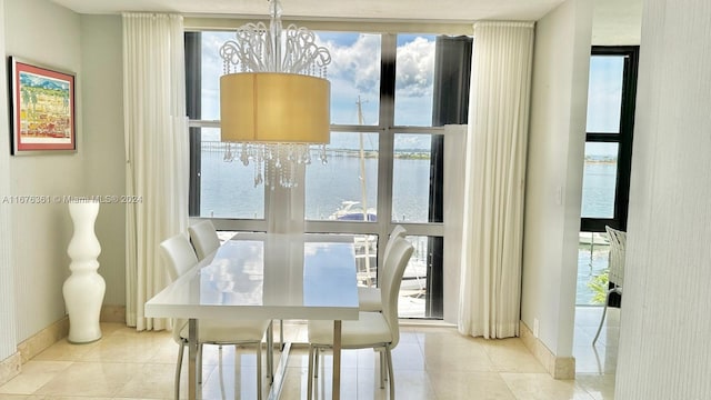 dining area featuring an inviting chandelier, a healthy amount of sunlight, a water view, and light tile patterned floors