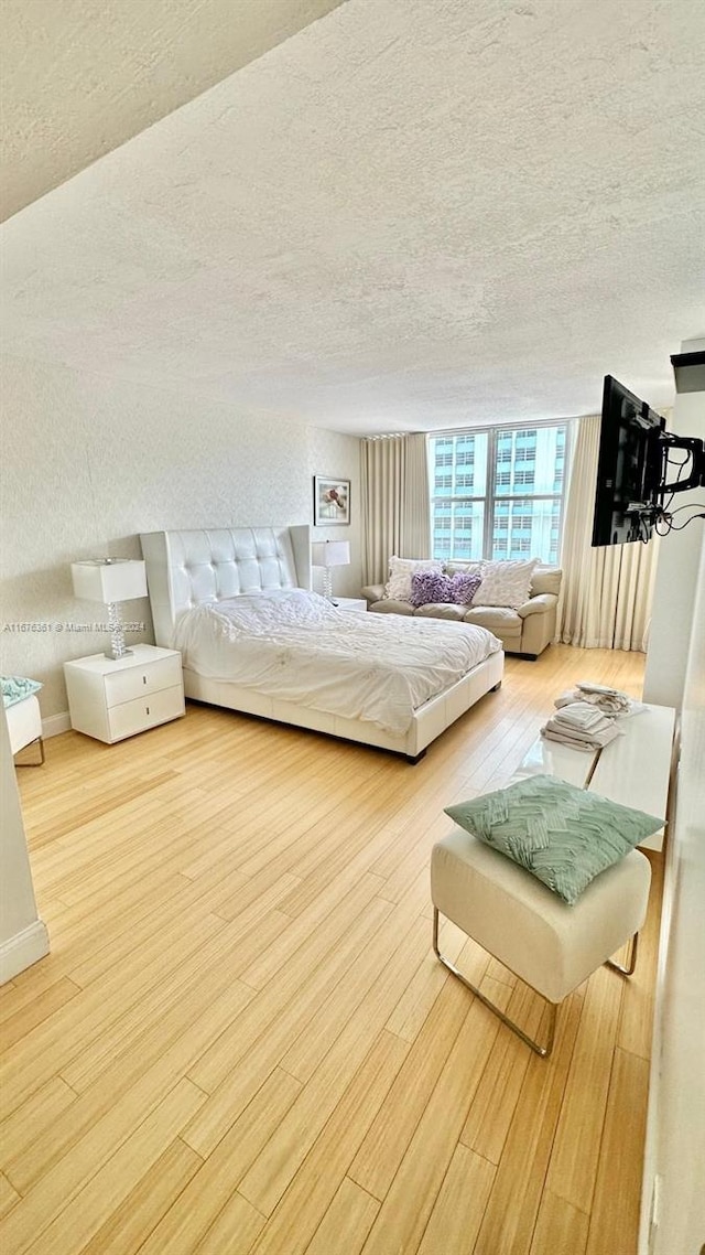 bedroom with a textured ceiling and light hardwood / wood-style flooring