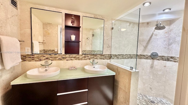 bathroom with vanity, a tile shower, and tile walls