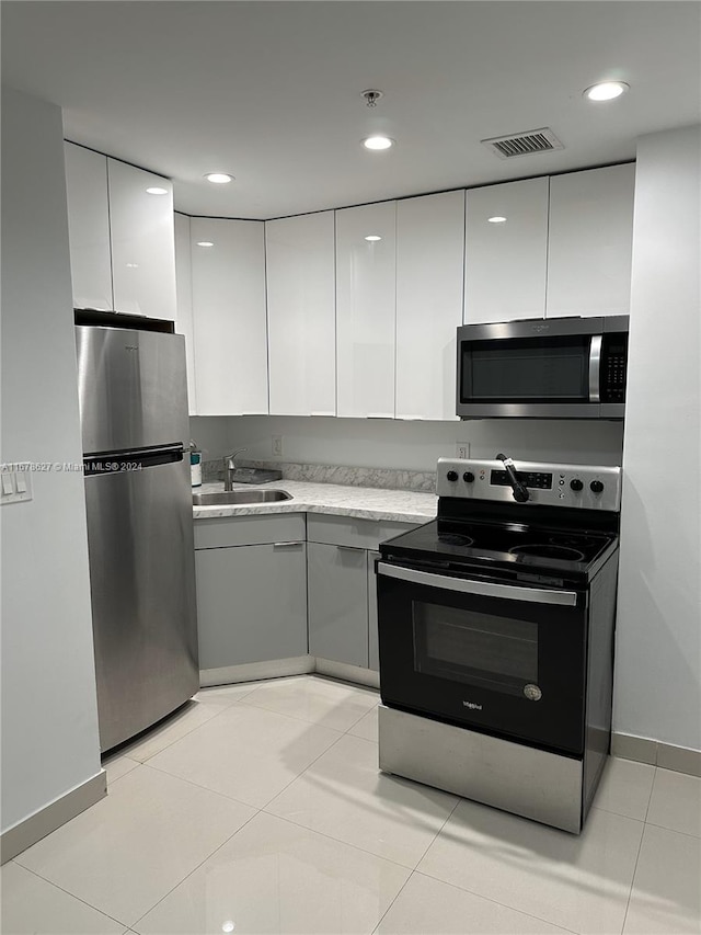 kitchen featuring appliances with stainless steel finishes, white cabinetry, sink, and light tile patterned floors