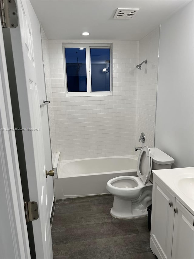 full bathroom with toilet, hardwood / wood-style floors, tiled shower / bath combo, and vanity