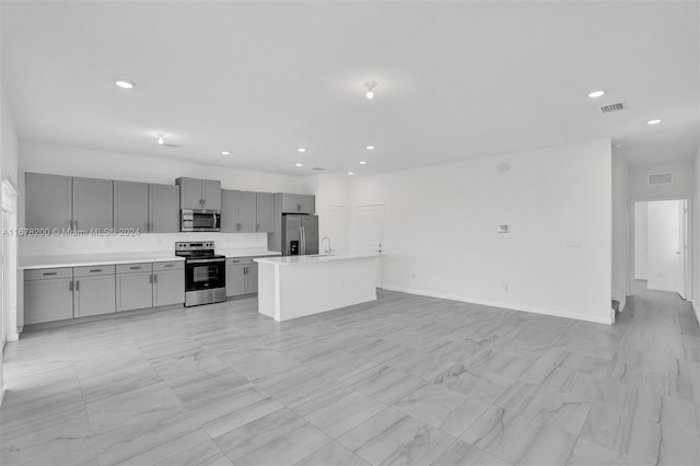 kitchen featuring appliances with stainless steel finishes, sink, a center island with sink, and gray cabinets