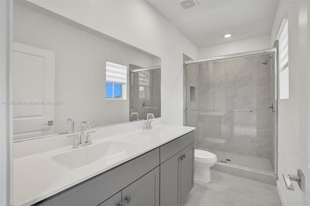 bathroom with vanity, toilet, tile patterned flooring, and a shower with door