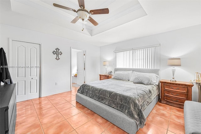 tiled bedroom featuring a closet, a raised ceiling, and ceiling fan