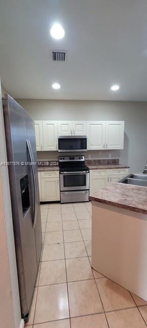 kitchen with white cabinets, stainless steel appliances, and light tile patterned floors