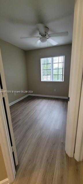 unfurnished room featuring dark wood-type flooring and ceiling fan