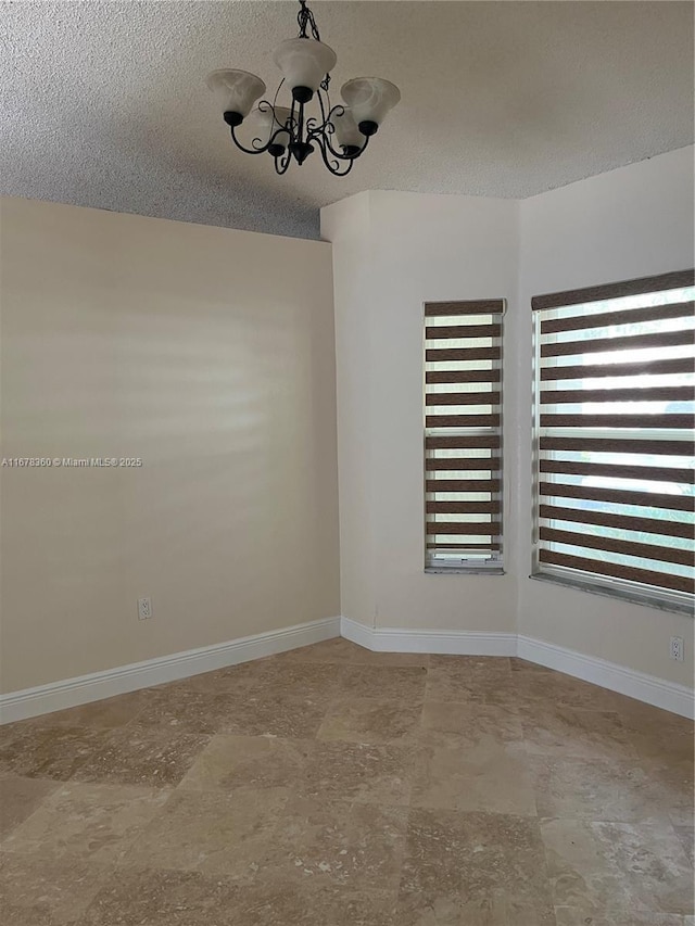 unfurnished room featuring a notable chandelier, plenty of natural light, and a textured ceiling