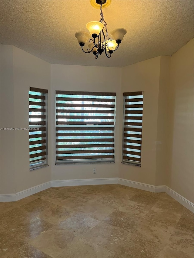 empty room featuring a textured ceiling and an inviting chandelier