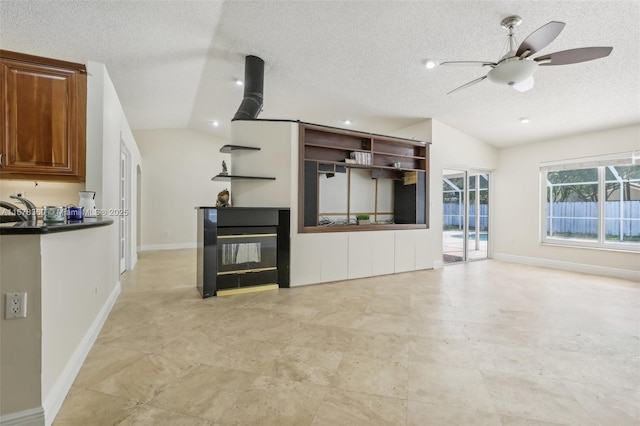 kitchen with a textured ceiling, vaulted ceiling, ceiling fan, and sink