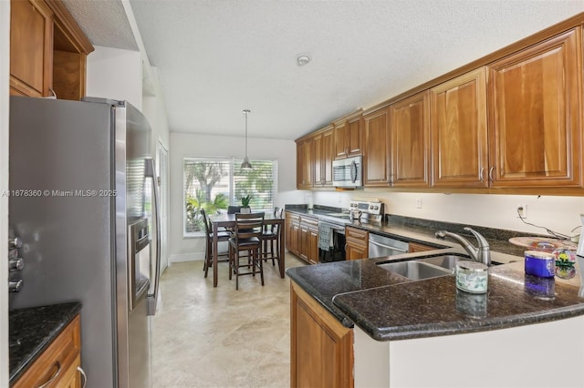 kitchen with sink, a textured ceiling, appliances with stainless steel finishes, decorative light fixtures, and kitchen peninsula