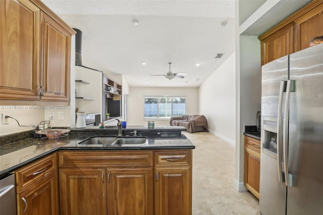 kitchen with stainless steel appliances, ceiling fan, dark stone countertops, and sink