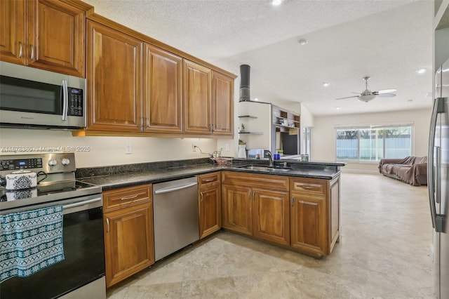 kitchen featuring kitchen peninsula, stainless steel appliances, vaulted ceiling, ceiling fan, and sink