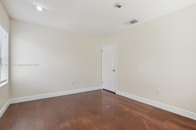 unfurnished room with dark wood-type flooring and a textured ceiling