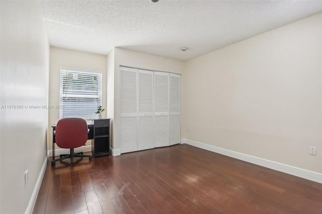 unfurnished office with a textured ceiling and dark hardwood / wood-style floors