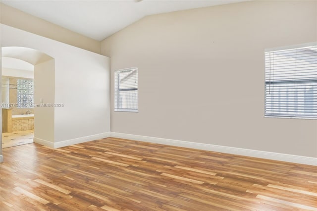 spare room featuring hardwood / wood-style flooring and lofted ceiling