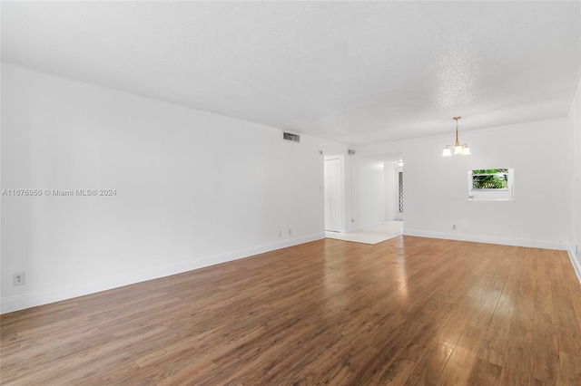 empty room featuring hardwood / wood-style floors, a textured ceiling, and a chandelier