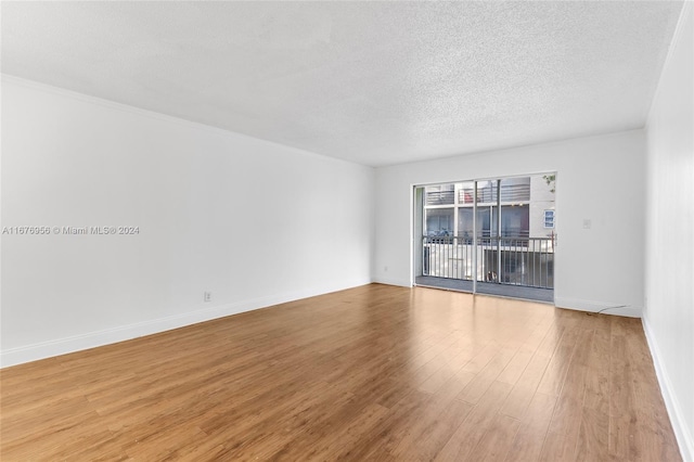 unfurnished room with light hardwood / wood-style flooring and a textured ceiling