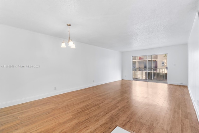 unfurnished room featuring a notable chandelier, a textured ceiling, and light hardwood / wood-style floors